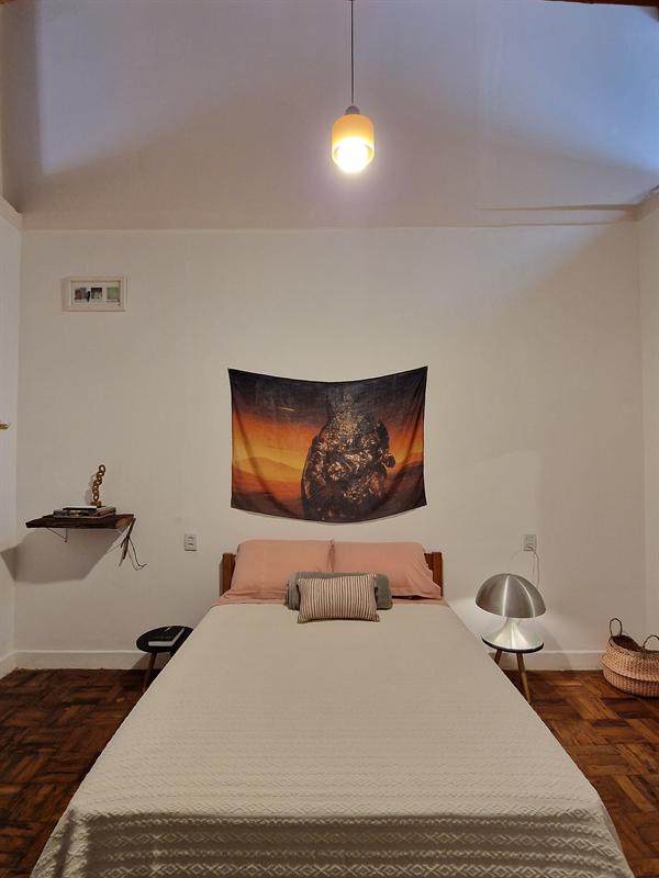 Cama de casal do Apartamento 1 com tapeçaria colorida acima da cabeceira