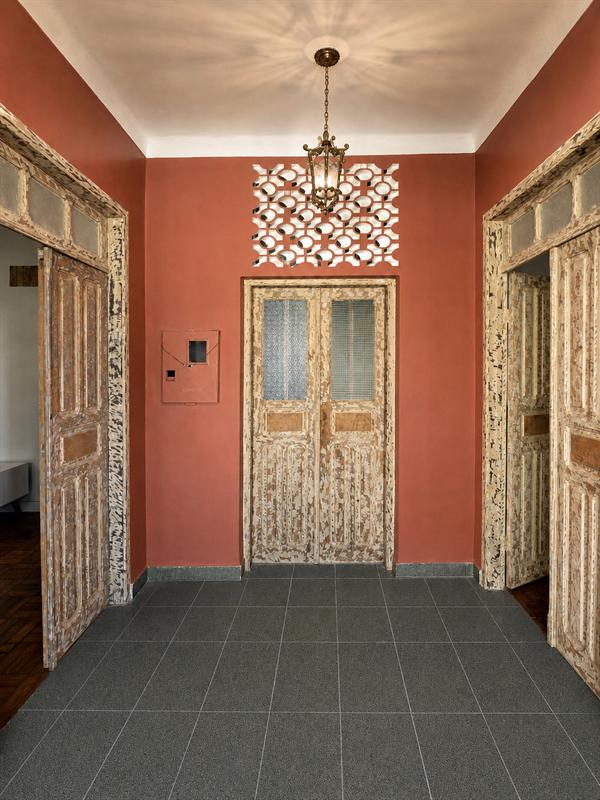 Hall de entrada com paredes terracota, portas antigas de madeira e luminária rendada