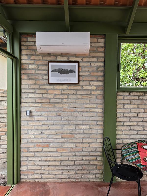 Ambiente com parede de tijolos, estrutura de aço verde, quadro e cadeira